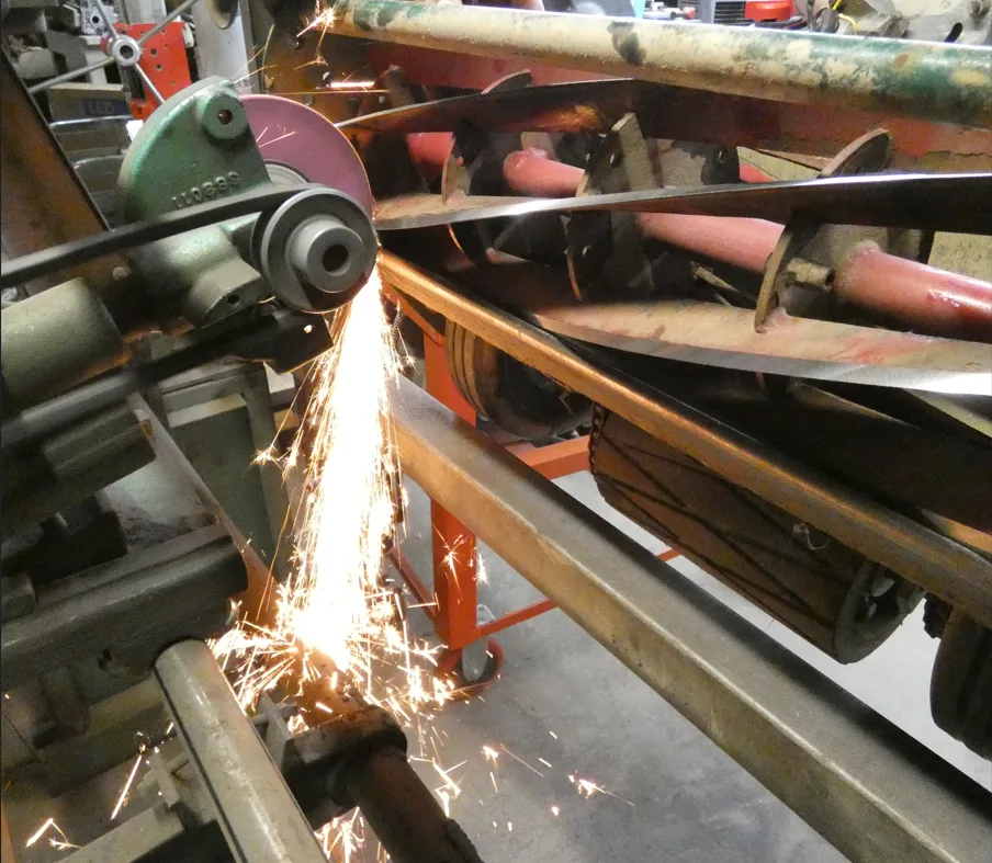 Sparks flying as a reel mower blade is relief ground on the sharpening machine in our shop